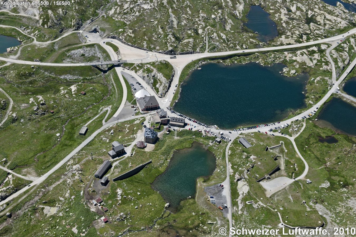 Ospizio San Gottardo, 2091 m.ü.M. (Position: 2'686'600.83, 1'156'692.44) Mit Hospiz-Gebäude (Hotel) und Kapelle; Bildmitte quadratisches Gebäude: Alte Sust (ehemals Auswechselstelle für Saumtiere, heute Restaurant und Gotthardmuseum); rechts unten: Festungsmuseum